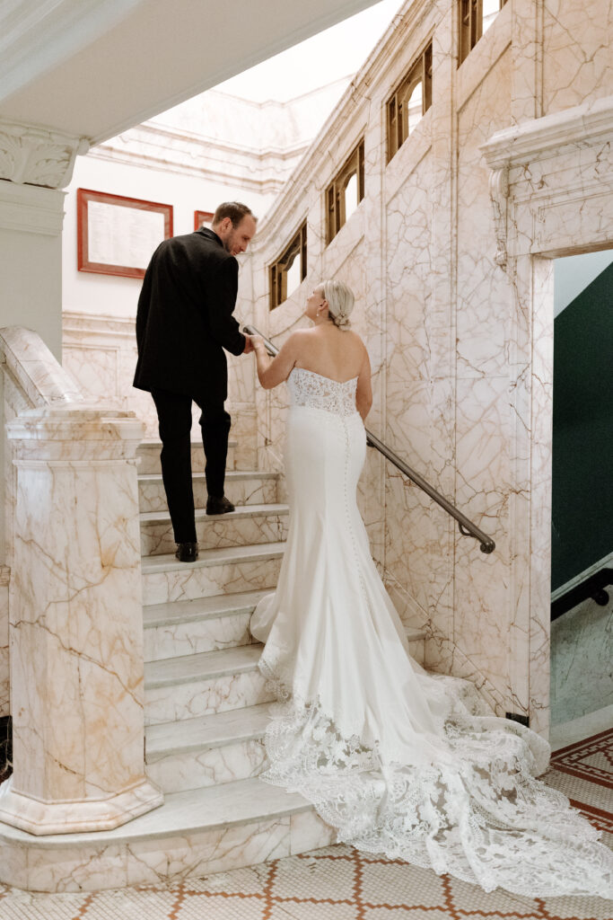 Bride and groom walk up marble staircase at the Cottonwood
