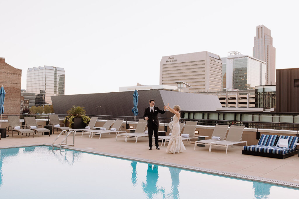 Bride and groom dance beside rooftop pool at Omaha Marriott Downtown
