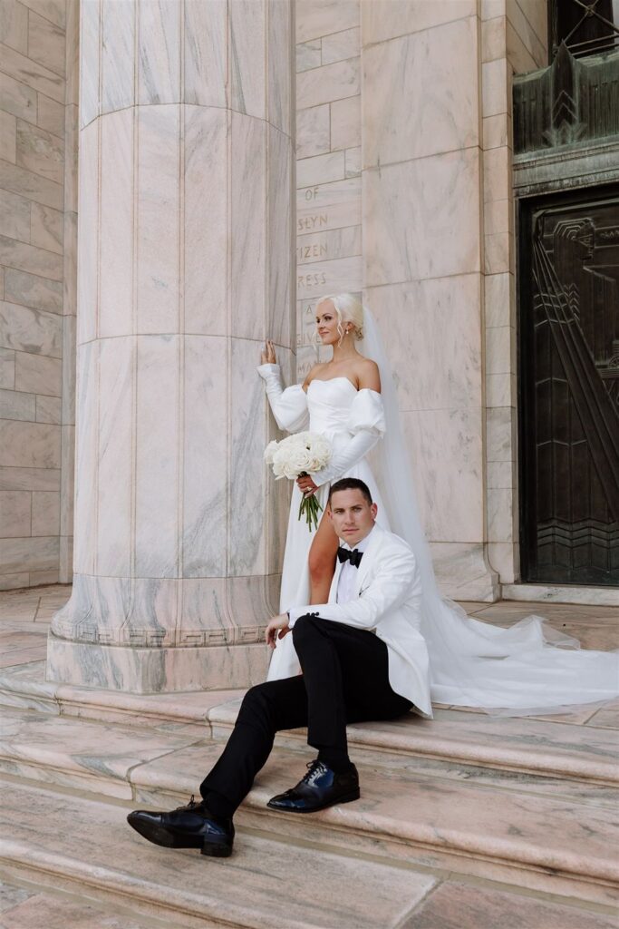 Newlyweds sit on the steps of The Joslyn Art Museum wedding venue.