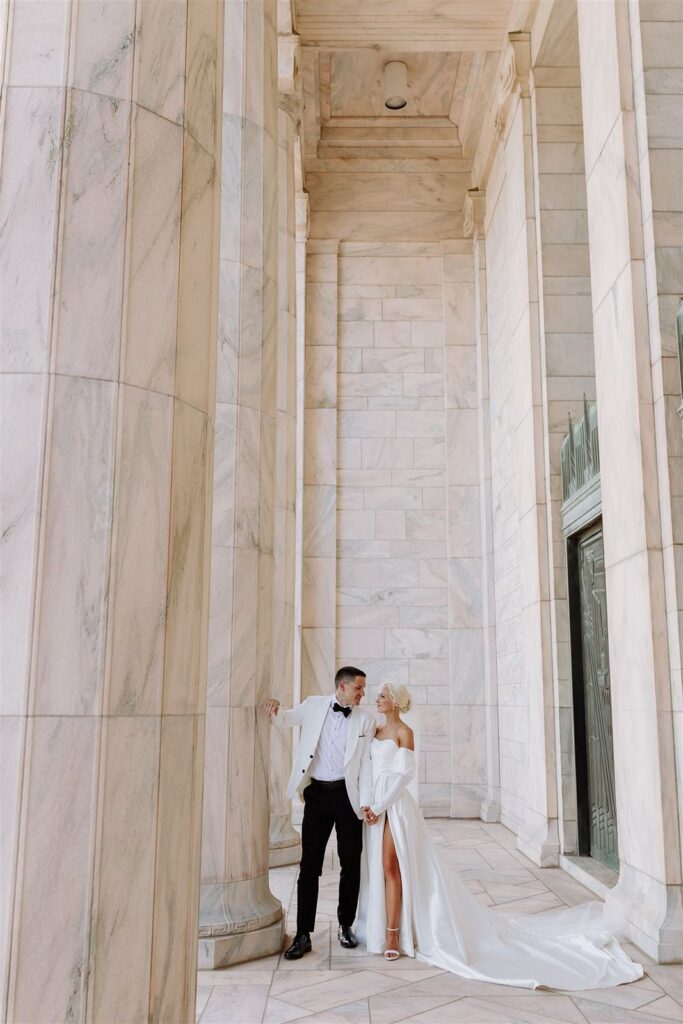Bride and groom next to marble column in front of The Joslyn in Omaha.